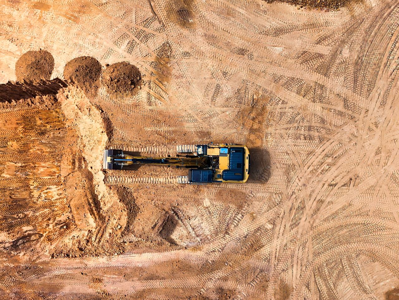 Home Aerial photo of an excavator working on a large empty construction site.