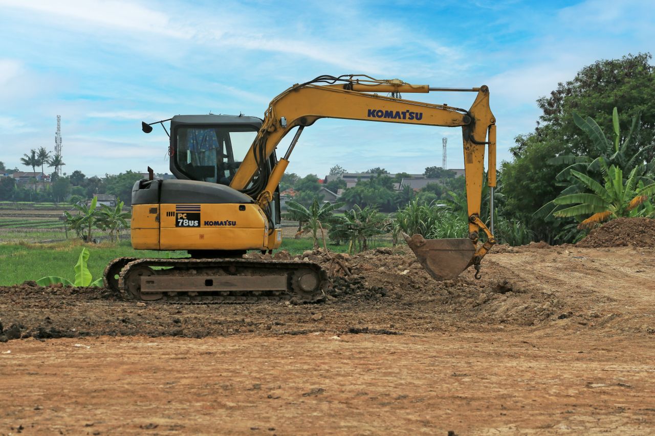 Home Yellow excavator on a rural construction site on a sunny day.